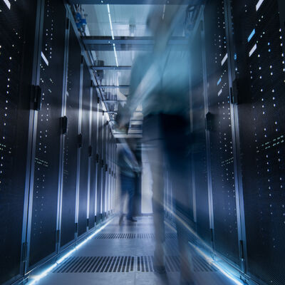 Aufnahme eines Korridors in einem gro&szlig;en Rechenzentrum voller sich bewegender und arbeitender Menschen.